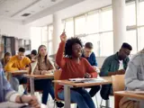 woman in classroom raising her hand